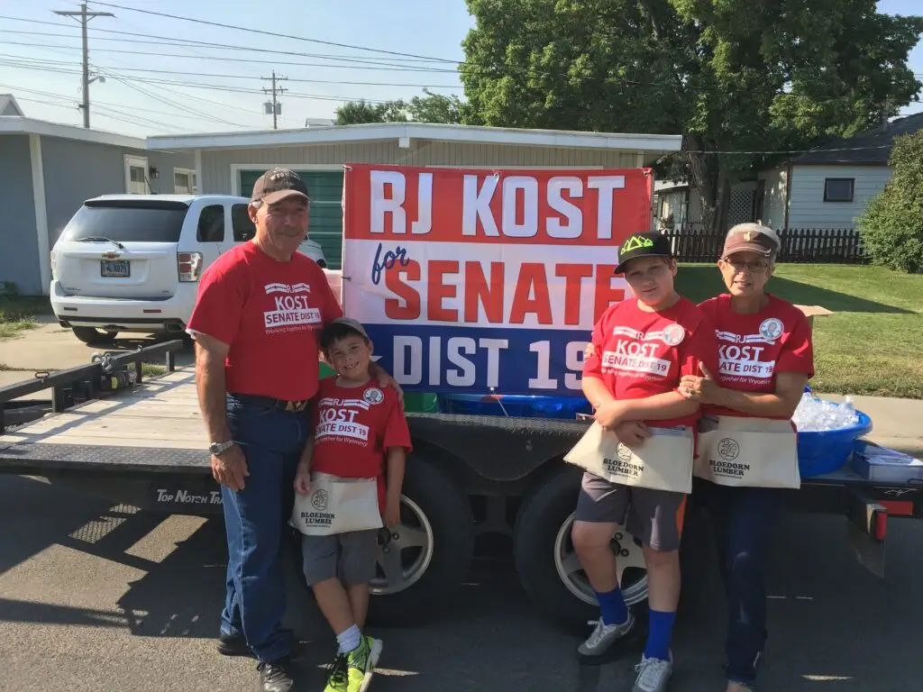 RJ Kost with family supporters in matching campaign shirts in front of “RJ Kost for Senate District 19” sign