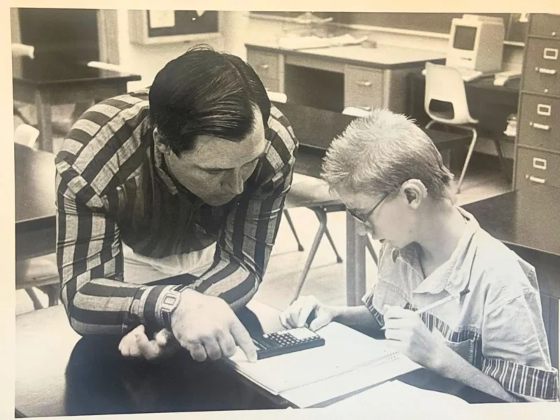 RJ Kost teaching a student in a classroom, demonstrating commitment to education and mentorship